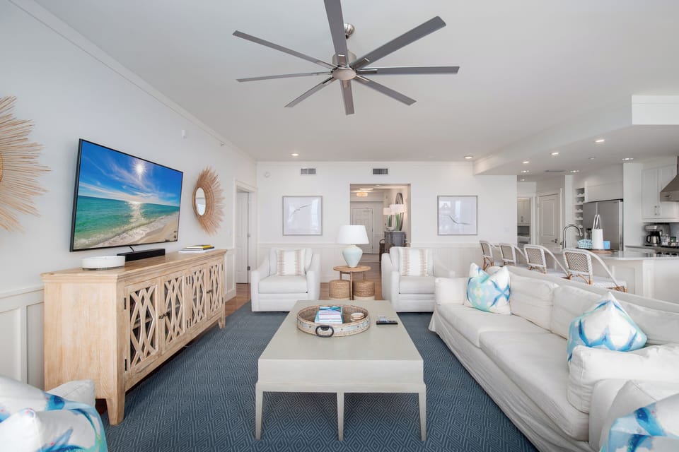 Relax in your bright coastal living room where ocean breezes flow from the ceiling fan above plush white sofas and beach-inspired décor.
