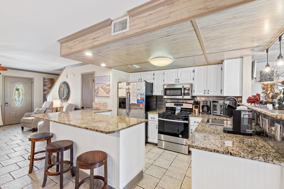 Fully stocked kitchen with 4 stools at the counter.
