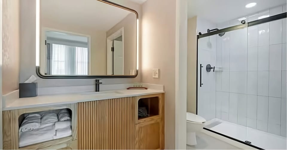 Refresh in a sleek bath with bright vanity lighting.