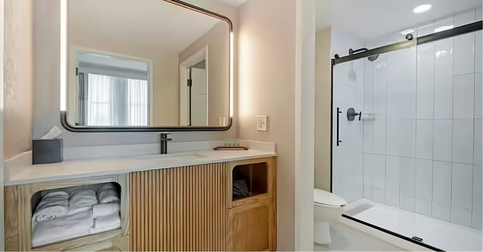 Refresh in a sleek bath with bright vanity lighting.