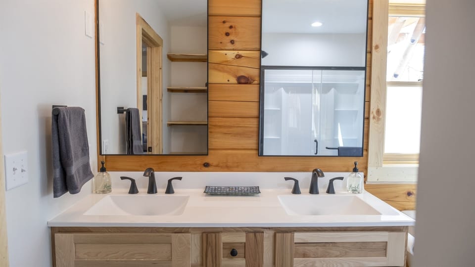 Master bathroom with double vanity, large shower, shelving, and natural light with privacy