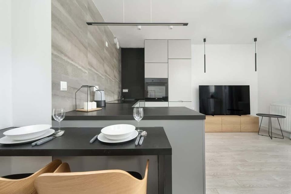 A compact and functional kitchen with an oven and electric hob. The dark countertop contrasts elegantly with the light tile backsplash.
