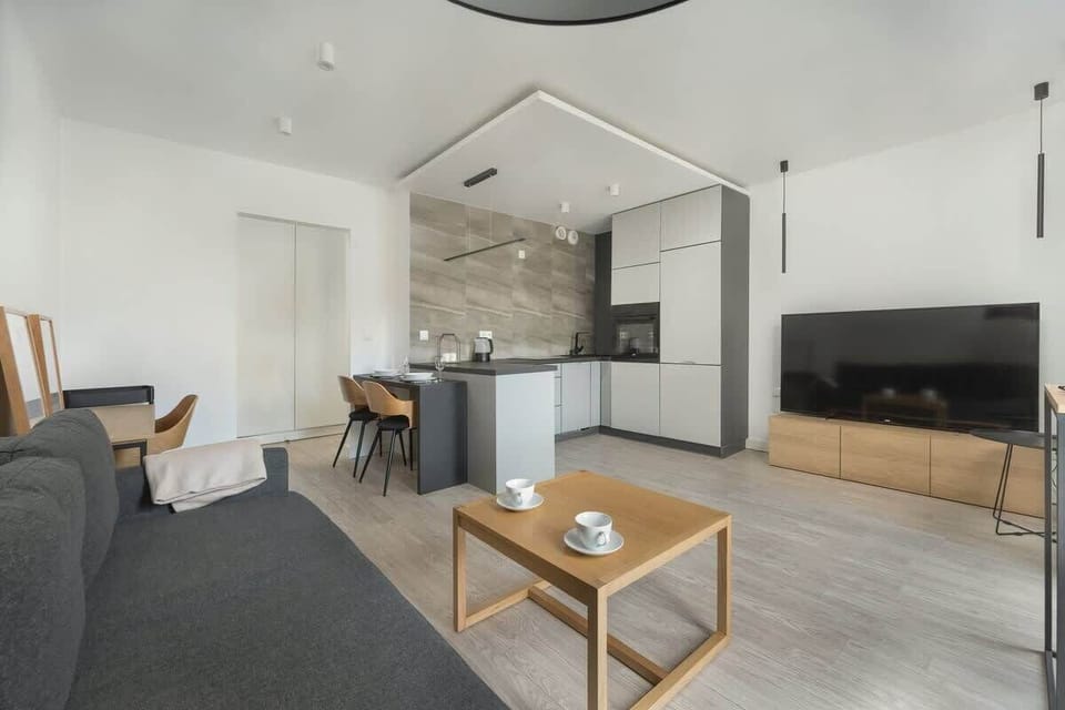 A bedroom area with a sofa bed, coffee table, and TV in the background. The room has a modern yet cozy ambiance.