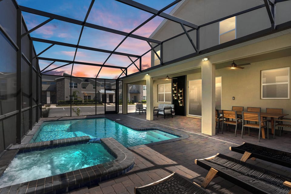Step into a vibrant outdoor oasis featuring a sparkling pool and bubbling spa, all framed by a sleek screened enclosure. The inviting dining area under soft lighting sets the tone for unforgettable evenings as the sun sets.