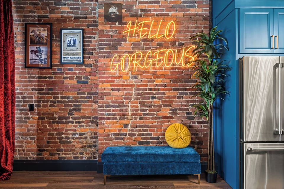 - Neon Hello Gorgeous sign with blue bench and brick wall adds vibrant character - Decorative accents complete this stylish downtown loft - Perfect photo moment for guests seeking a fun trendy interior