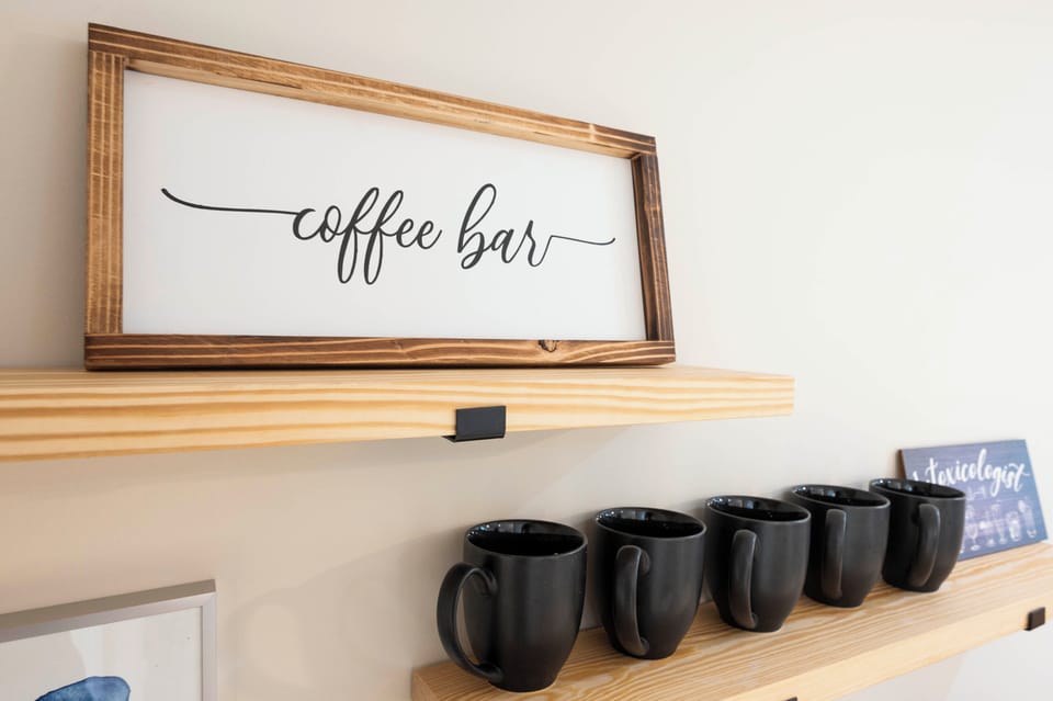 Cozy coffee bar with black mugs on wooden shelves, creating a warm vibe.