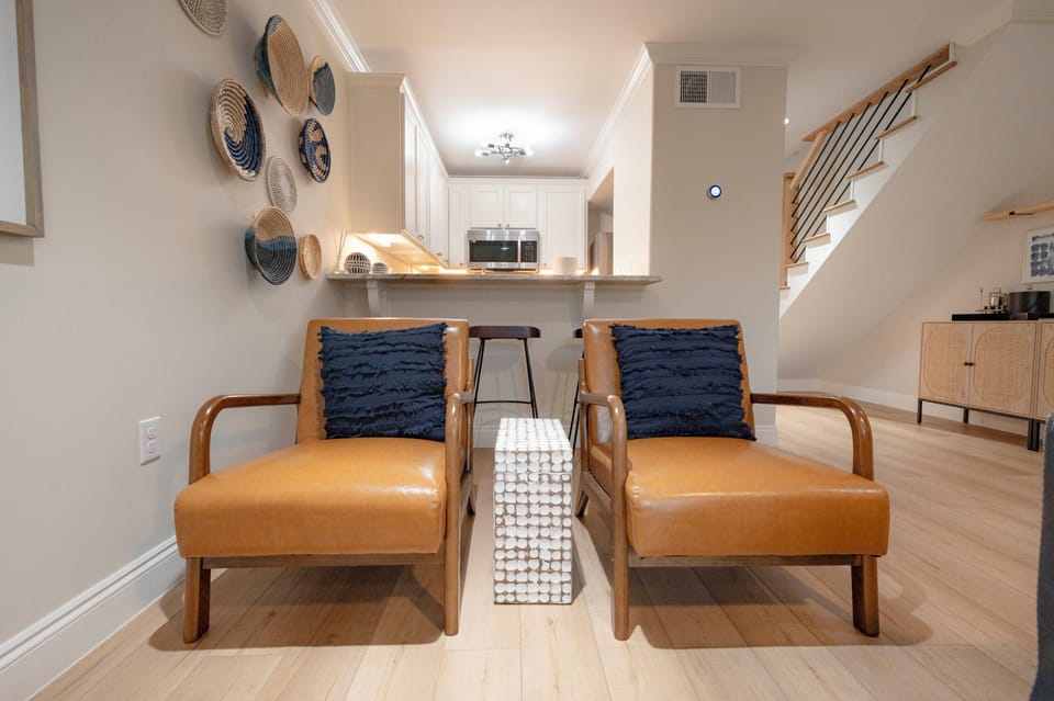 Relax in a modern living room with cozy leather chairs and a sleek kitchen.