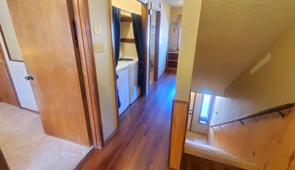Bright, welcoming hallway with warm wood floors connecting you to your in-unit washer and dryer—one less thing to worry about during your stay.