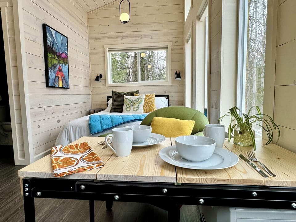 Enjoy the comfort of the queen bed, with a Murphy table alongside, set for dining. Cups, plates, sauces, and cutlery are all provided for your convenience