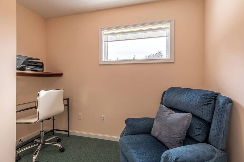 Flexible office/nursery space off the primary bedroom, complete with a recliner chair, office desk, printer, and a cozy window nook—ideal for remote work or quiet moments with little ones.