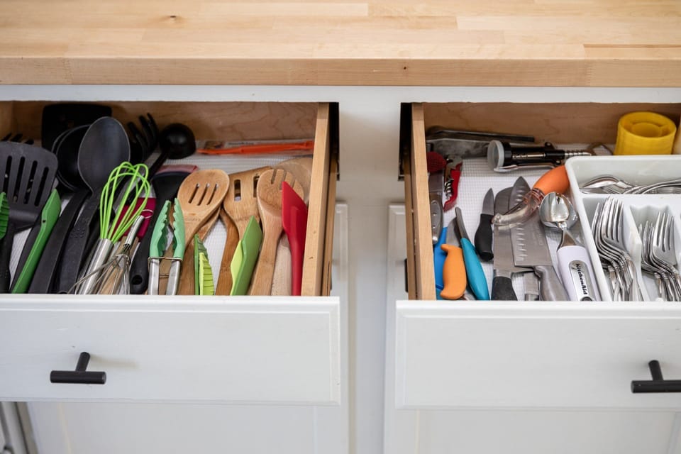 Kitchen drawers, one housing cooking utensils and the other storing cutlery, display an array of tools, all poised and ready for your culinary endeavors.