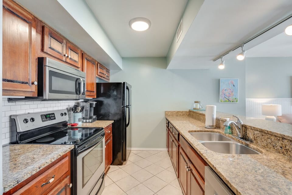 Cook up coastal meals with ease in the fully equipped kitchen featuring granite countertops, stainless steel appliances, and warm wood cabinetry. Whether you`re preparing a quick snack or a family dinner, this space has everything you need.
