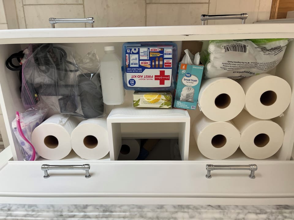 Bathroom vanity drawer with a variety of supplies.  Hairdryer. 
