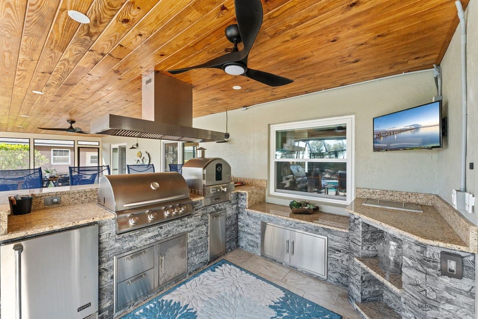 Fire up the grill in this dreamy outdoor kitchen with granite counters, a ceiling fan, and everything you need for a laid-back cookout.