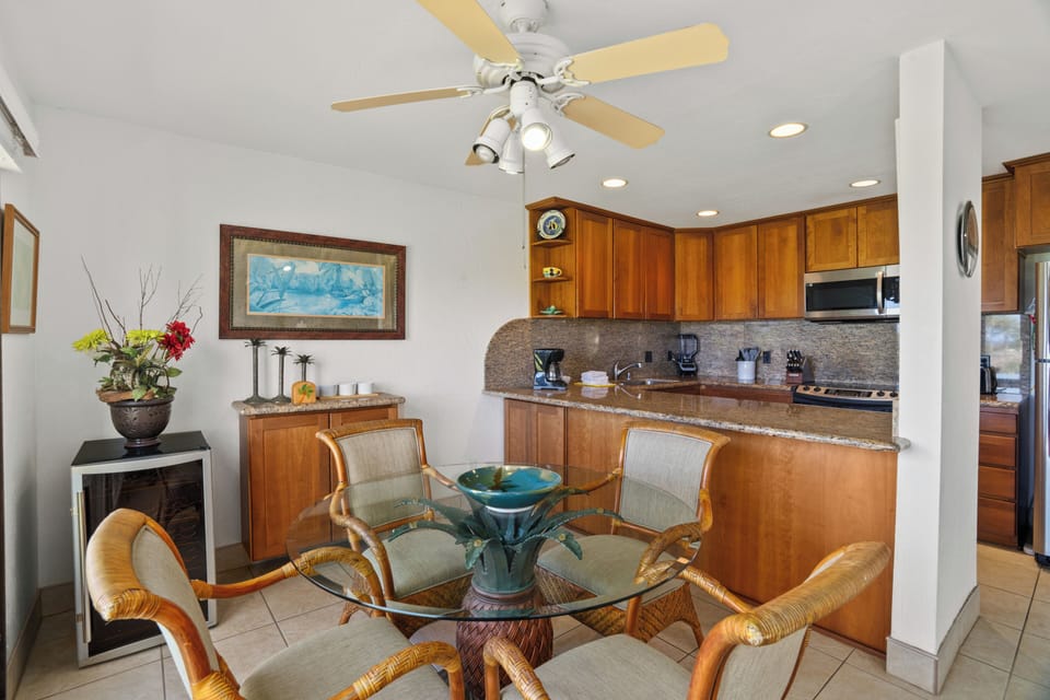 Gather around this inviting dining area where warm wood tones meet tropical comfort. The fully equipped kitchen stands ready for your culinary adventures while ocean breezes keep you cool.