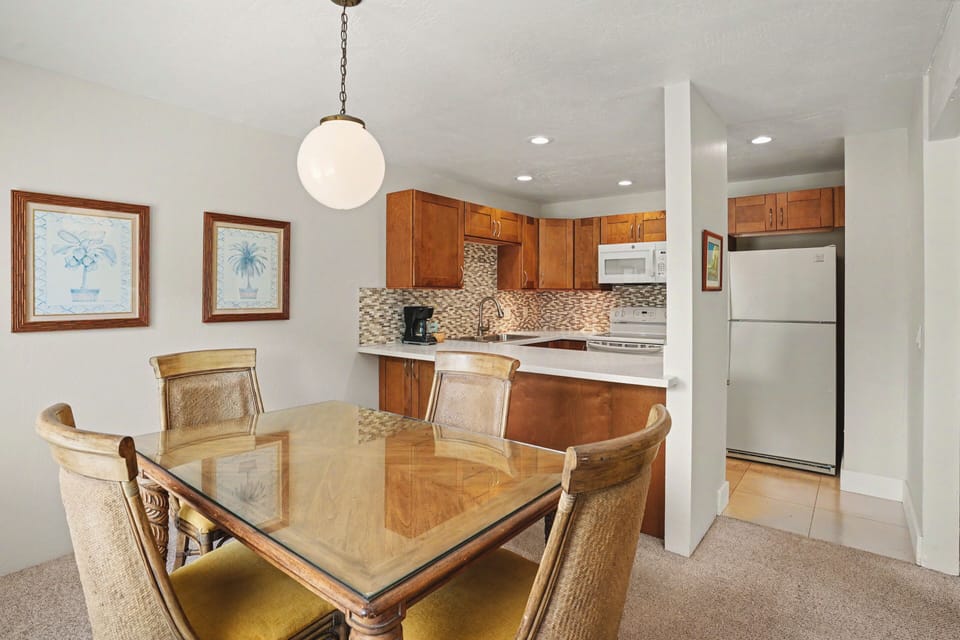 Picture yourself savoring morning coffee at the elegant glass-topped dining table, then stepping into your well-appointed kitchen with warm wood cabinetry, modern appliances, and stylish tile backsplash—everything you need for your perfect vacation getaway