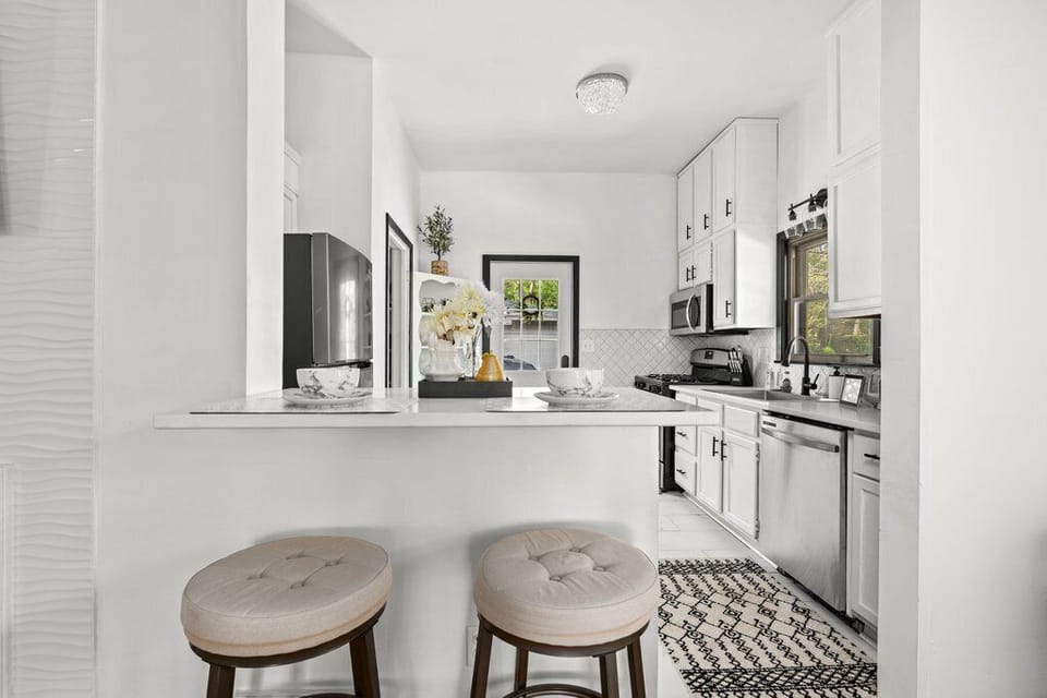 Modern kitchen with white cabinets, island, and stainless steel appliances.