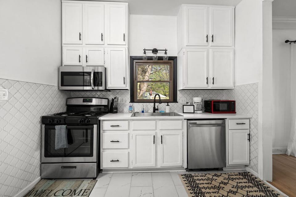 Well-equipped kitchen with white cabinetry and quartz countertops.