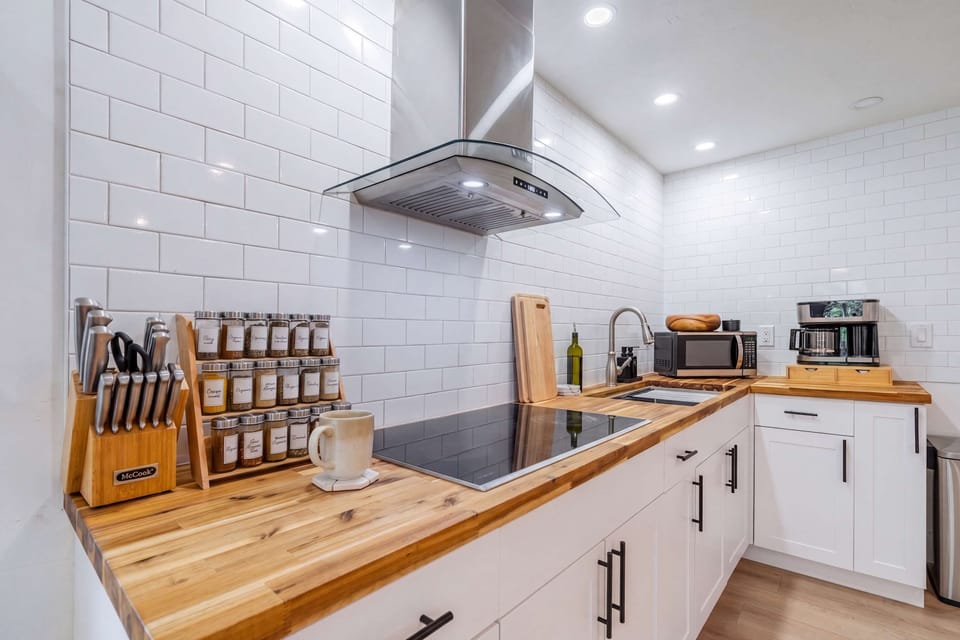 A cook’s dream! This modern kitchenette features sleek butcher block countertops, a high-end induction cooktop, and a fully stocked spice rack. 