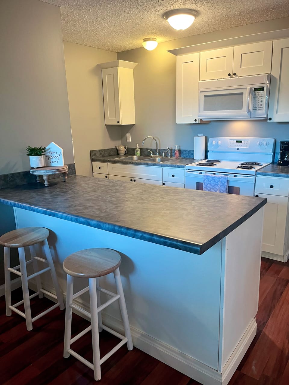 Kitchen has 2 bar seats and a table with 4 chairs. 