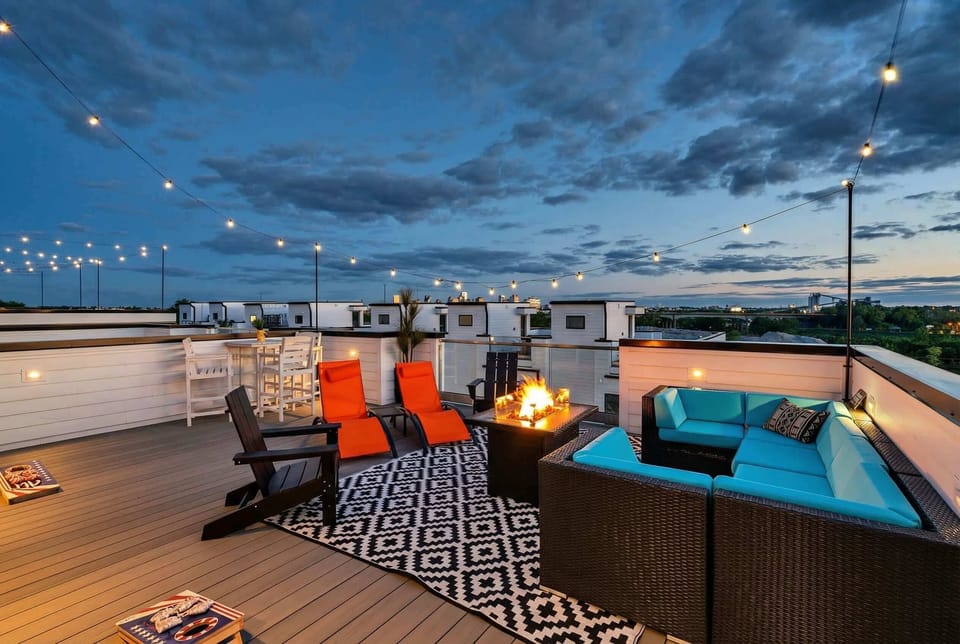 String lights glow across the rooftop deck as fire glows in the pit and city lights shimmer beyond. Grab a lounge chair, a drink, and watch the evening unfold from your own private escape