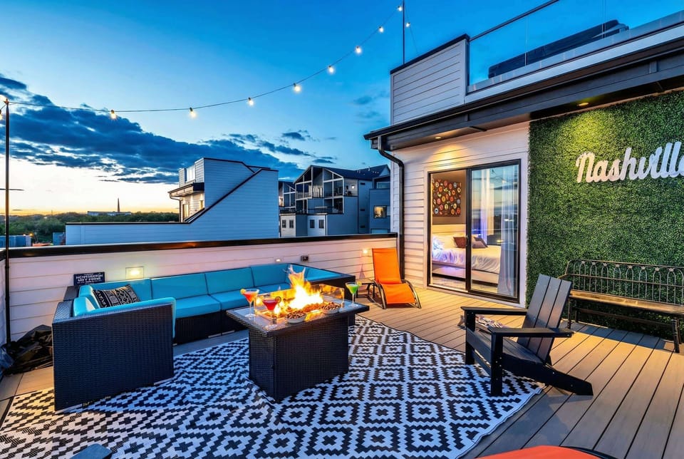 Rooftop hot tub surrounded by lounge seating, a fire pit, and a Nashville sign glowing under string lights, your sunset moment is ready to happen