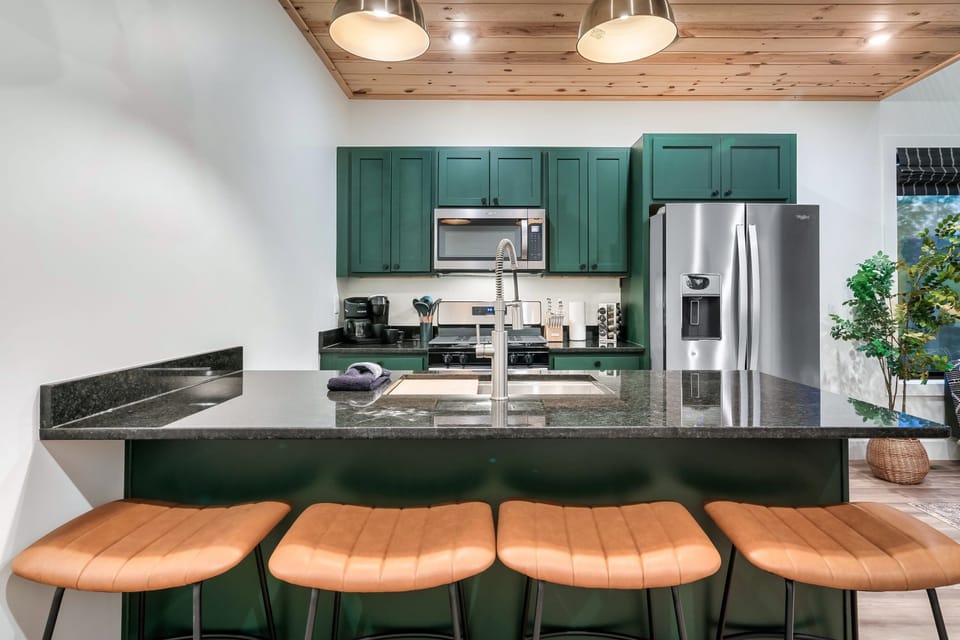 Sleek green cabinetry and modern amenities invite culinary adventures in style!