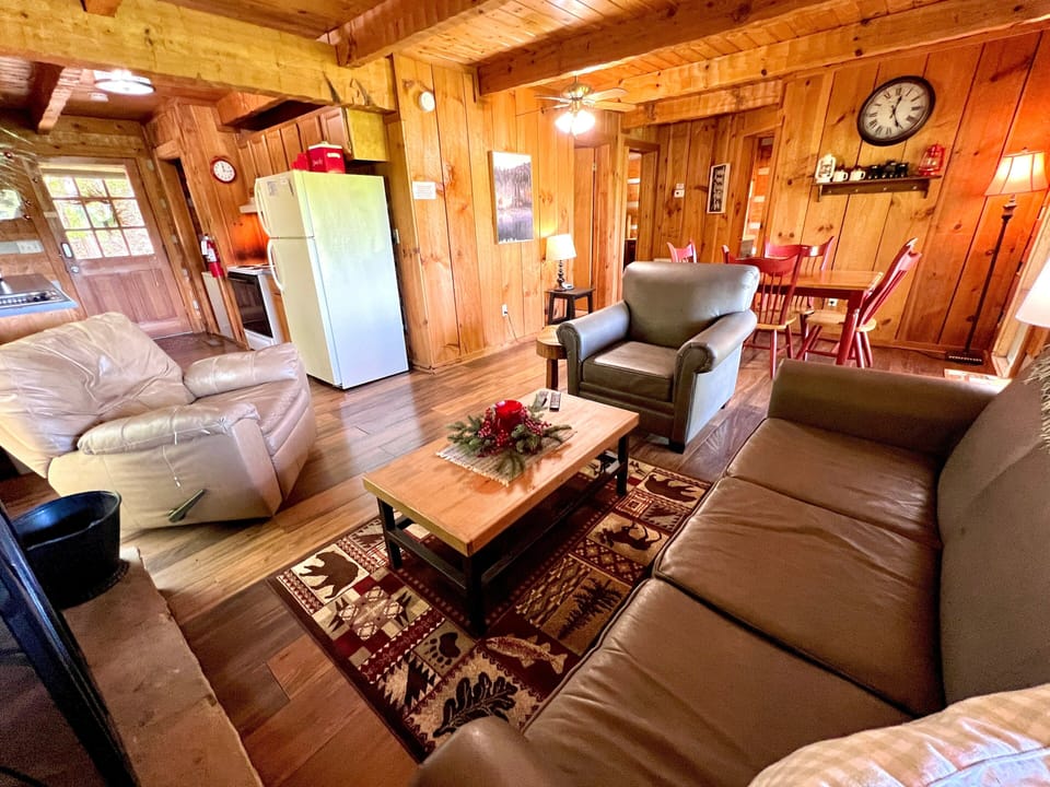 Wide angle view of open living and dining area with fireplace, sofa, and rustic wood decor at Bearadise Found cabin in Pigeon Forge, Tennessee