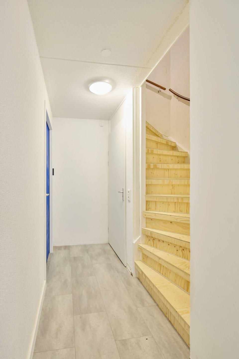 Minimalist corridor with warm wooden staircase. The way up to the apartment. 