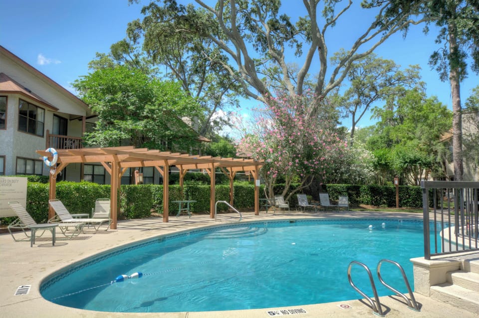 Harbour Oaks Community Pool - Community pool with lounge chairs, pergola shade, fencing, and mature trees.