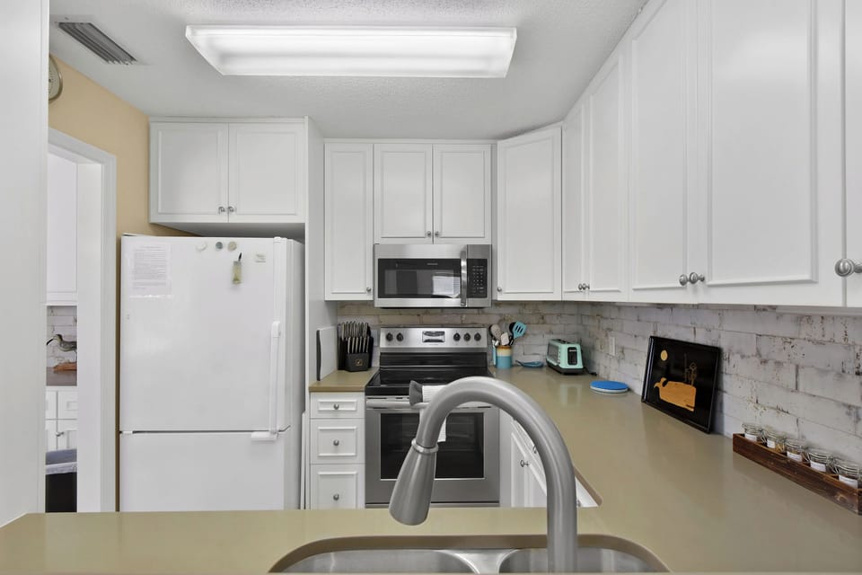 Kitchen with Subway Tile - Kitchen with white cabinetry, full-size appliances, sink, and subway tile backsplash.
