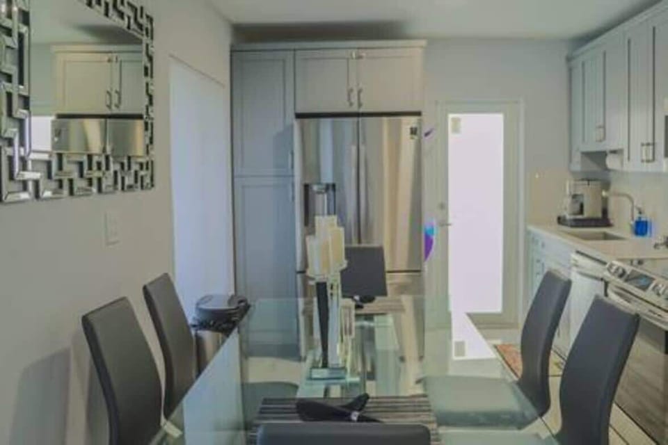 Sleek, modern kitchen with stainless steel appliances, ample cabinet space, and a glass dining table for six. Perfectly equipped for cooking and dining, offering a stylish and functional space for your stay. Ideal for comfort and convenience.