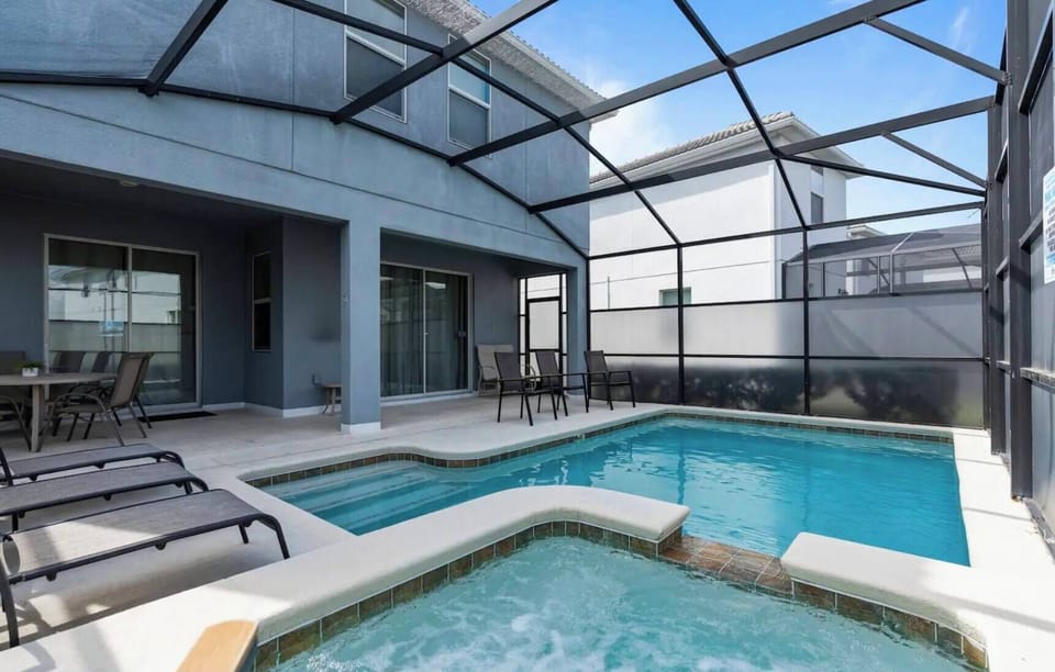 Step into your private oasis featuring a sparkling pool and a soothing spa, all enclosed by a sleek screened-in patio. The modern design and ample natural light create a refreshing atmosphere, perfect for relaxation and leisure.