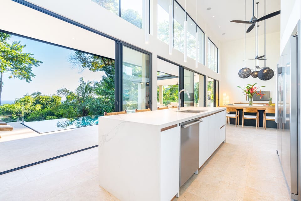 Open-plan kitchen and living area with glass doors and forest views.
