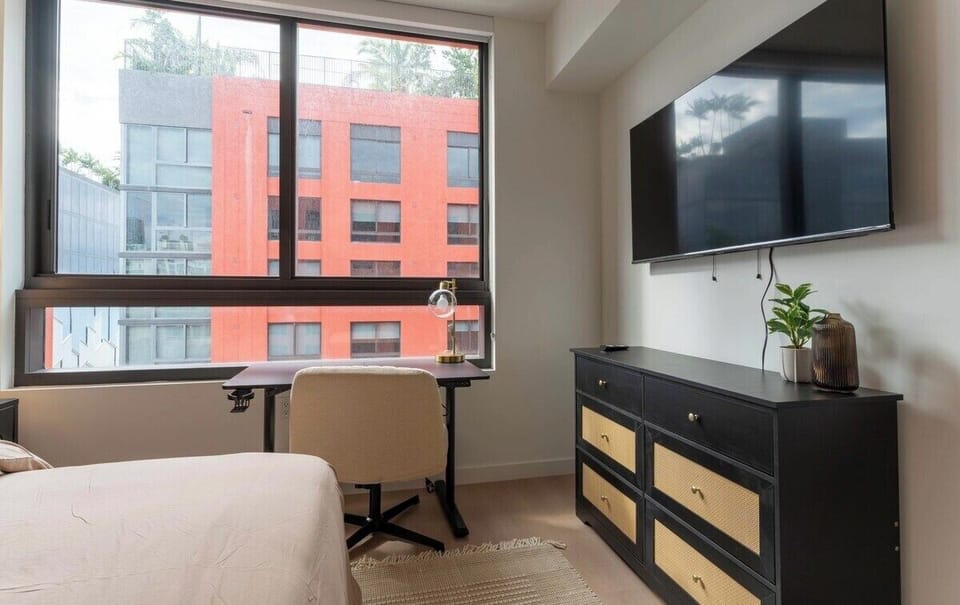 Bedroom with a queen-size bed, dedicated workspace, and TV