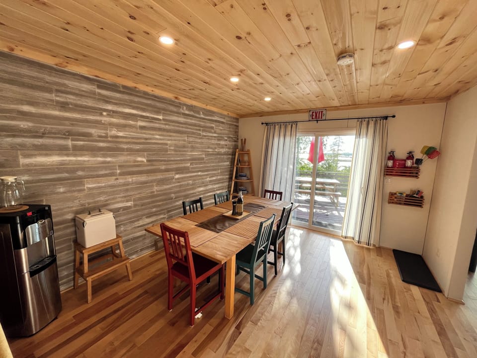 Bright dining area with colorful chairs, a sturdy wooden table, and direct access to the outdoor deck through sliding glass doors, perfect for enjoying meals with a view.