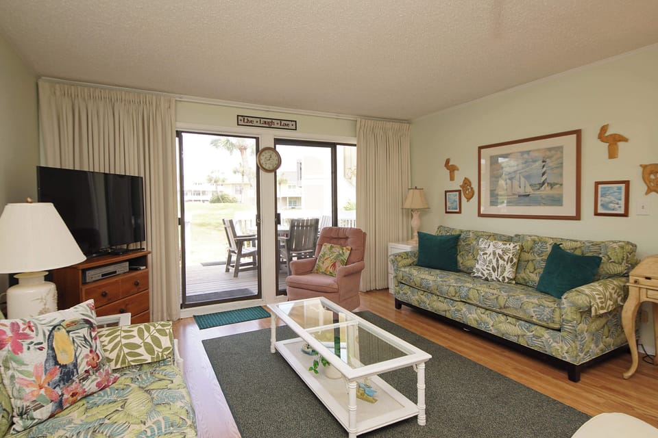 Relax in your tropical-themed living room with comfy seating, flat-screen TV, and easy access to your private patio.