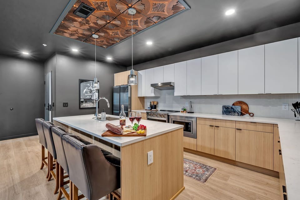 The fully equipped modern kitchen features culinary essentials, stainless steel appliances, and island bar seating.