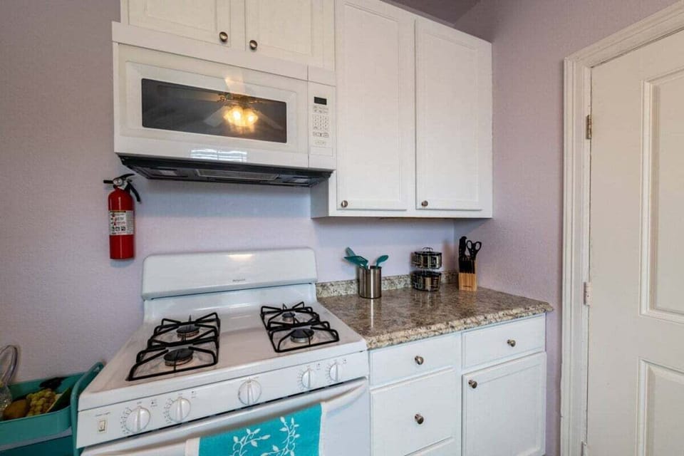 Kitchen with gas stove, microwave, granite countertops, and modern white cabinetry designed for convenient cooking during beach getaways.