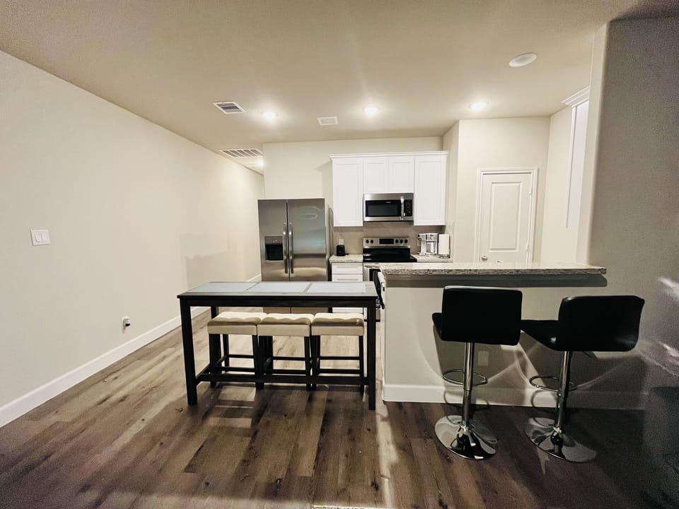 Open kitchen with Bisto table and bar area w/ stools.
