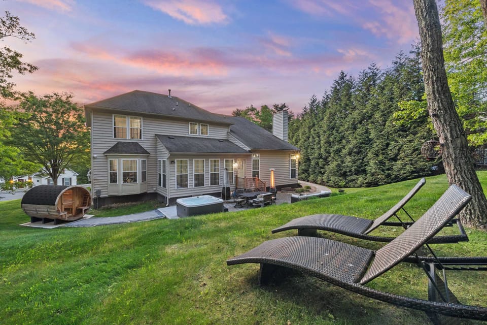 
Step outside as the sky turns purple and the hot tub jets kick on — barrel sauna steaming on one side, string-lit lawn stretching out on the other.