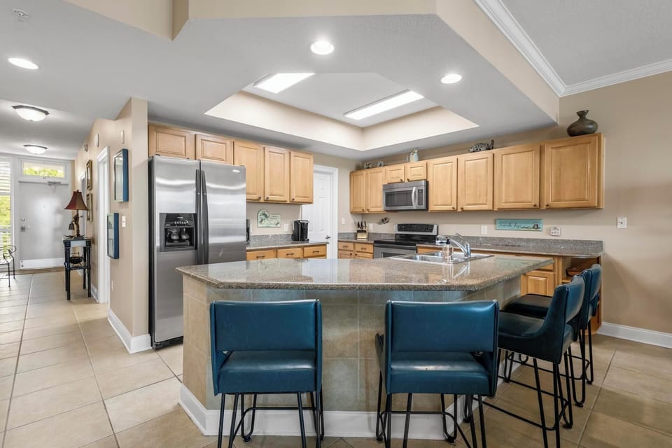 Kitchen - The spacious kitchen features stainless appliances, which include a dishwasher, smooth cooktop range, built in microwave, and side by side refrigerator. Each cabinet is fully stocked with all items needed for preparing meals during your stay.