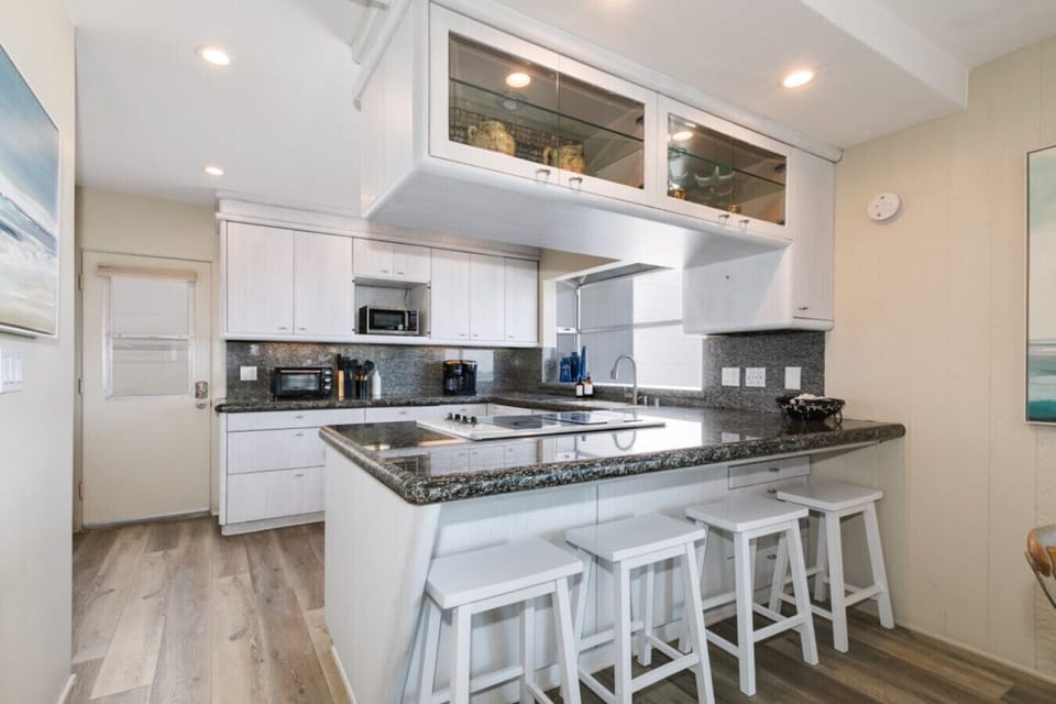 Features white cabinetry, granite countertops, and a breakfast bar with seating for four, perfect for casual meals or morning coffee with a view.