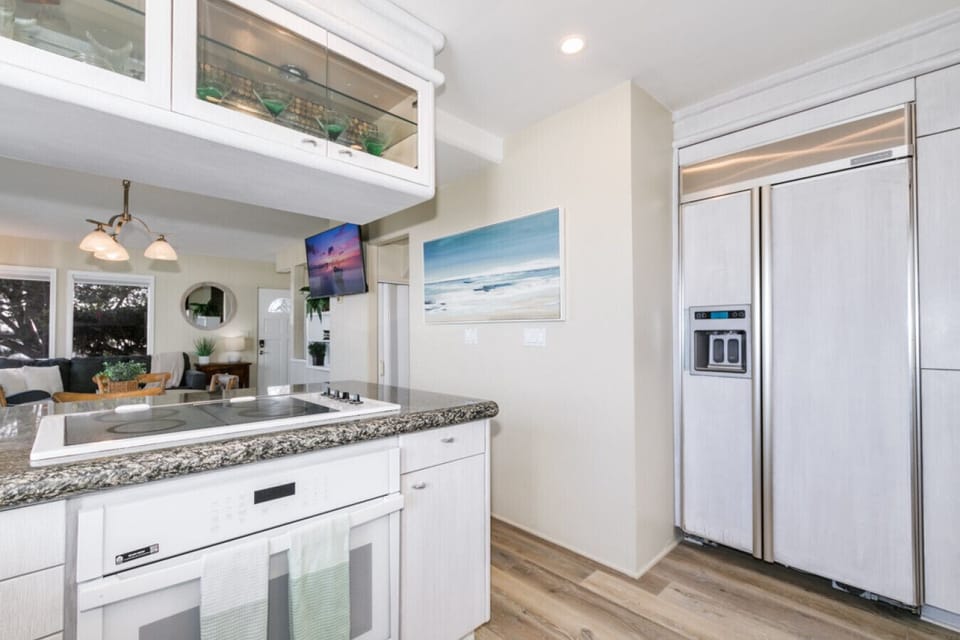 Fully equipped kitchen featuring a large refrigerator and cooktop, set against a backdrop of stunning beach views, perfect for preparing family meals.