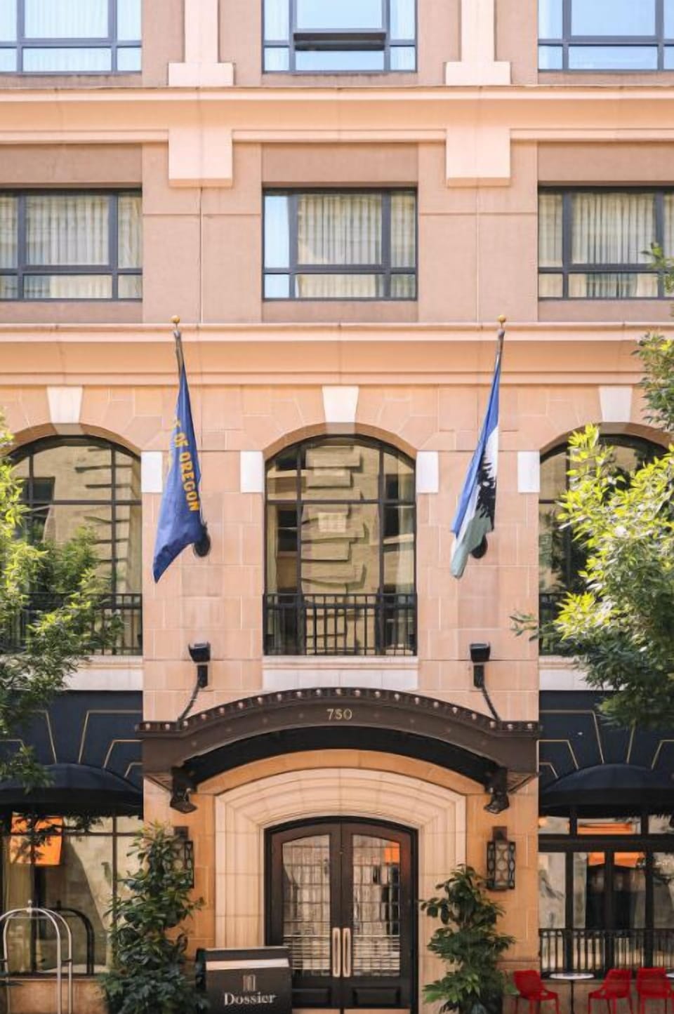 The charming facade of Hotel Dossier, accented with flags, welcomes guests with a promise of exceptional service and a memorable visit.