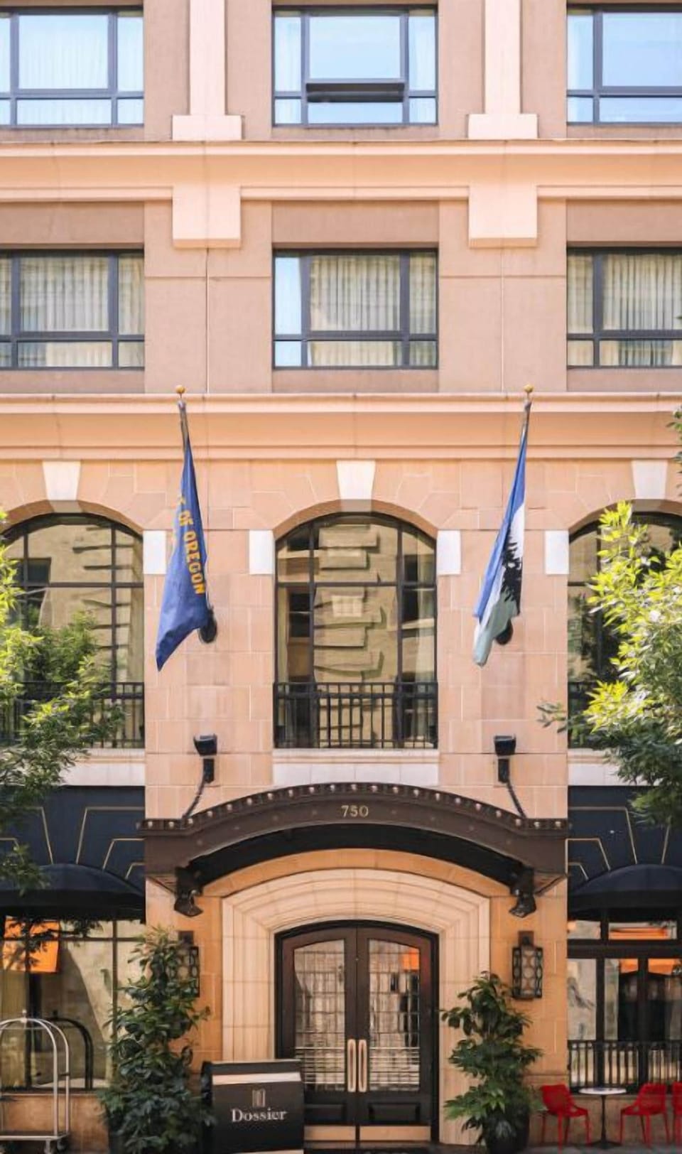 The charming facade of Hotel Dossier, accented with flags, welcomes guests with a promise of exceptional service and a memorable visit.