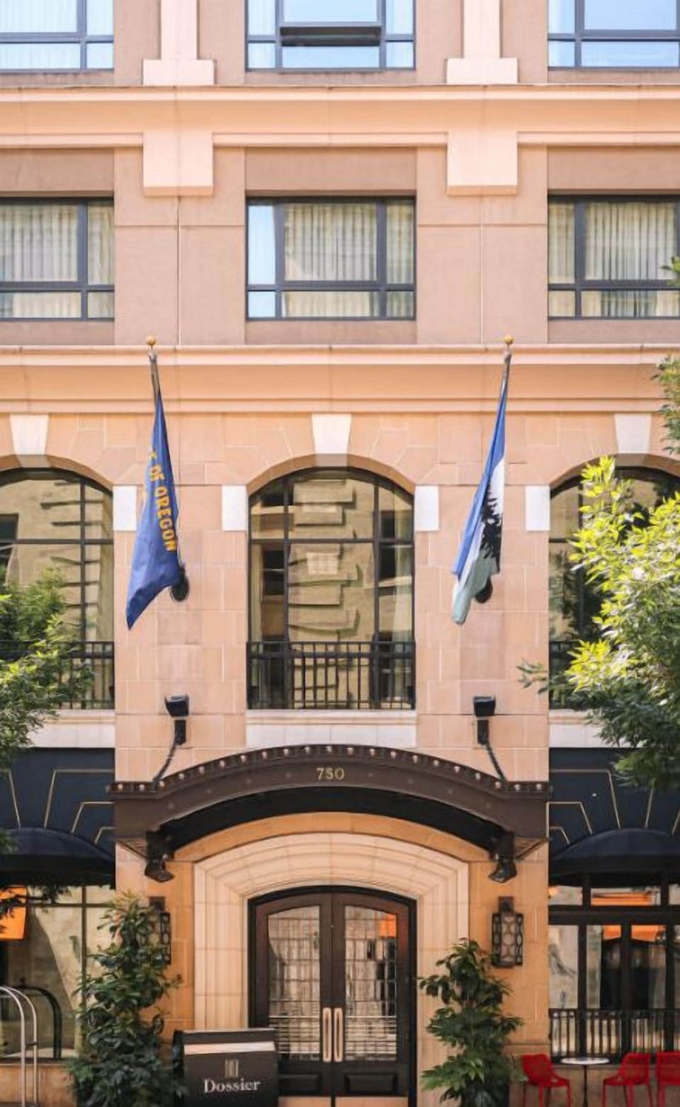 The charming facade of Hotel Dossier, accented with flags, welcomes guests with a promise of exceptional service and a memorable visit.