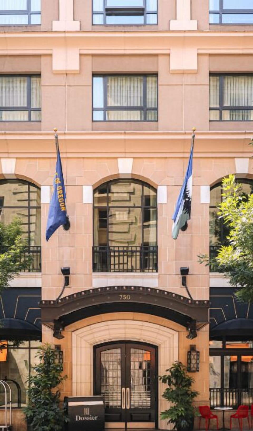 The charming facade of Hotel Dossier, accented with flags, welcomes guests with a promise of exceptional service and a memorable visit.
