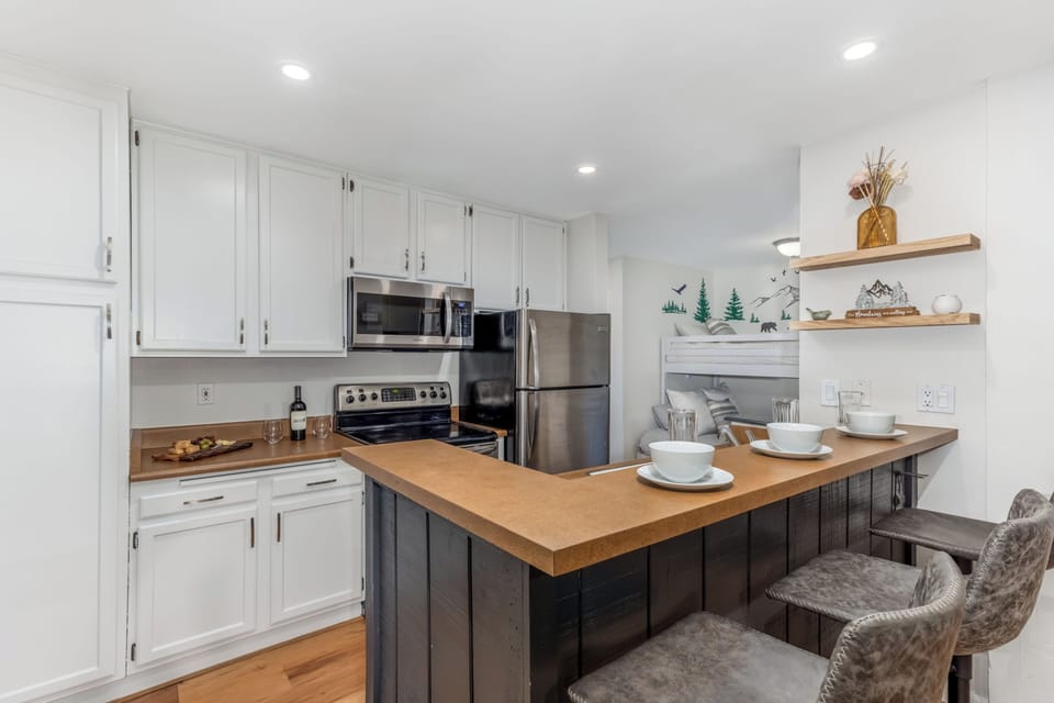 Clean, bright kitchen 🍽️✨ with bar seating and nearby bunk nook 🌲 for the kids