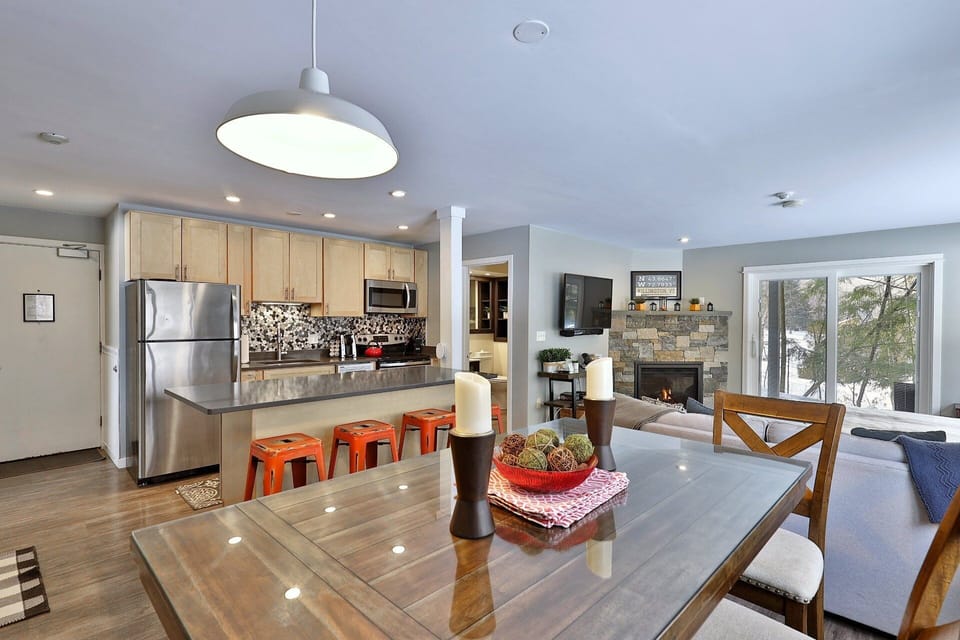 On the other side of the main suite is the open kitchen, a kitchen island with seating for four, and a high-top dining table with seating for six.